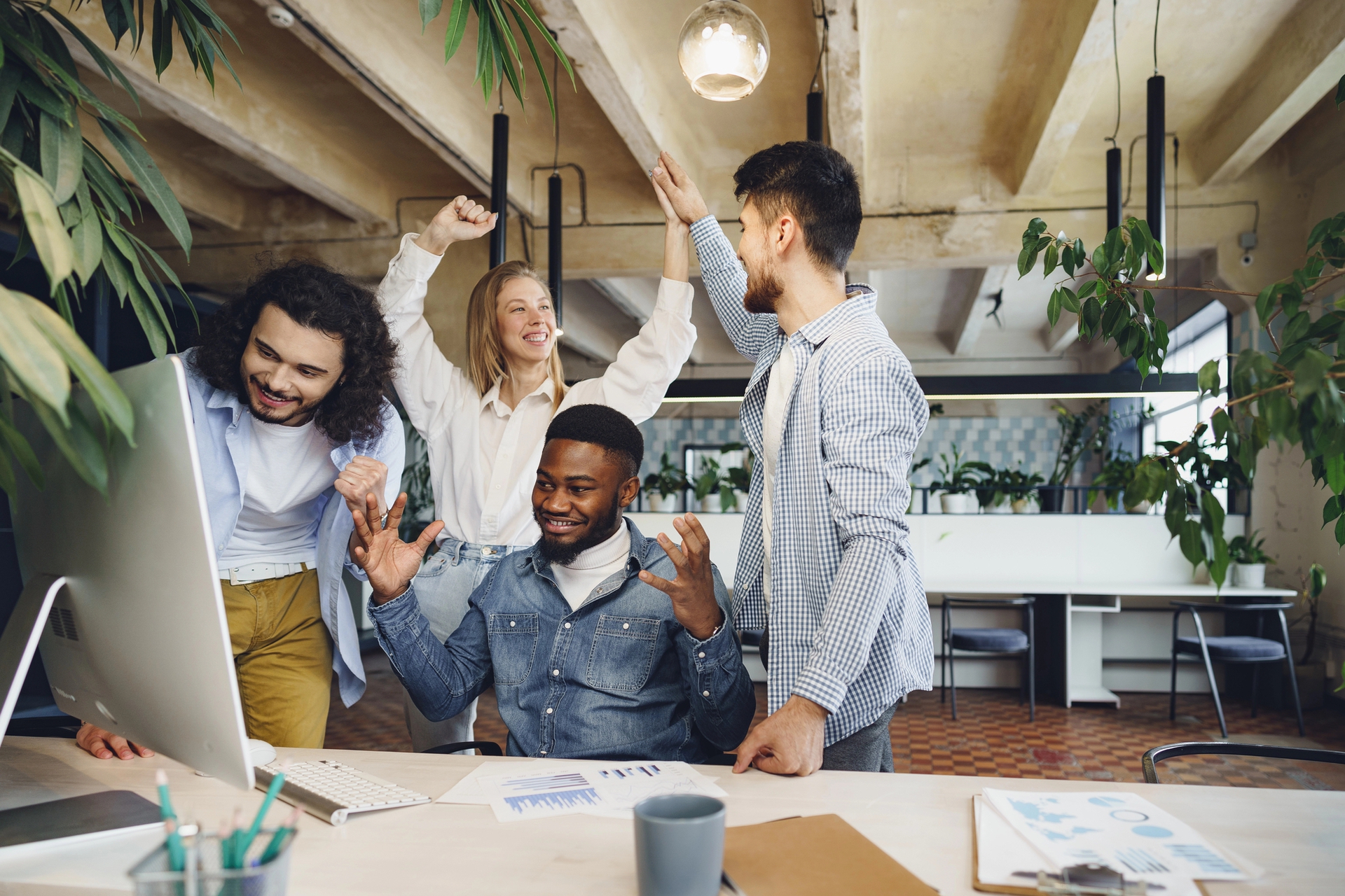 team high fiving around a computer